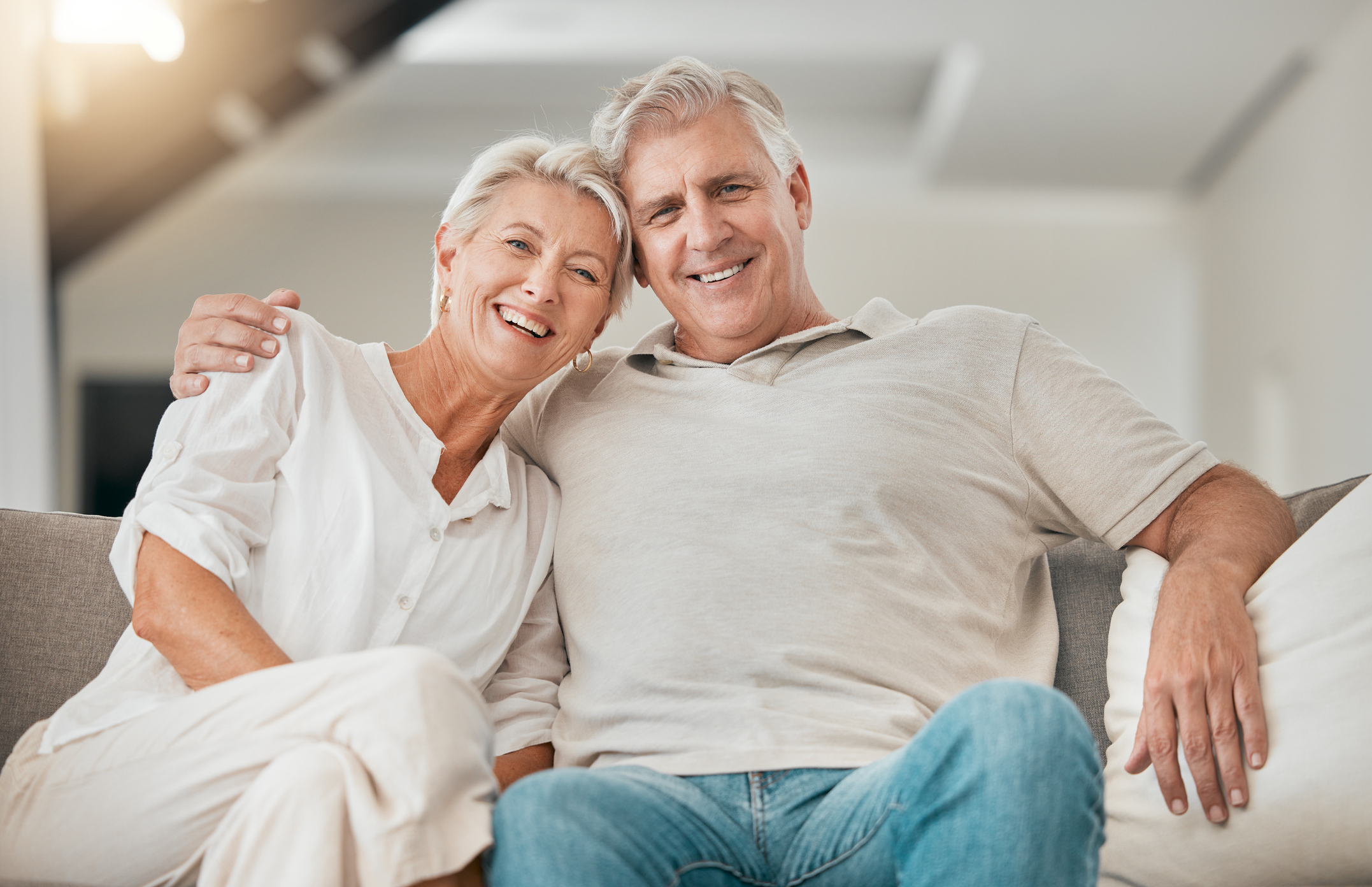 happy senior couple on living room couch