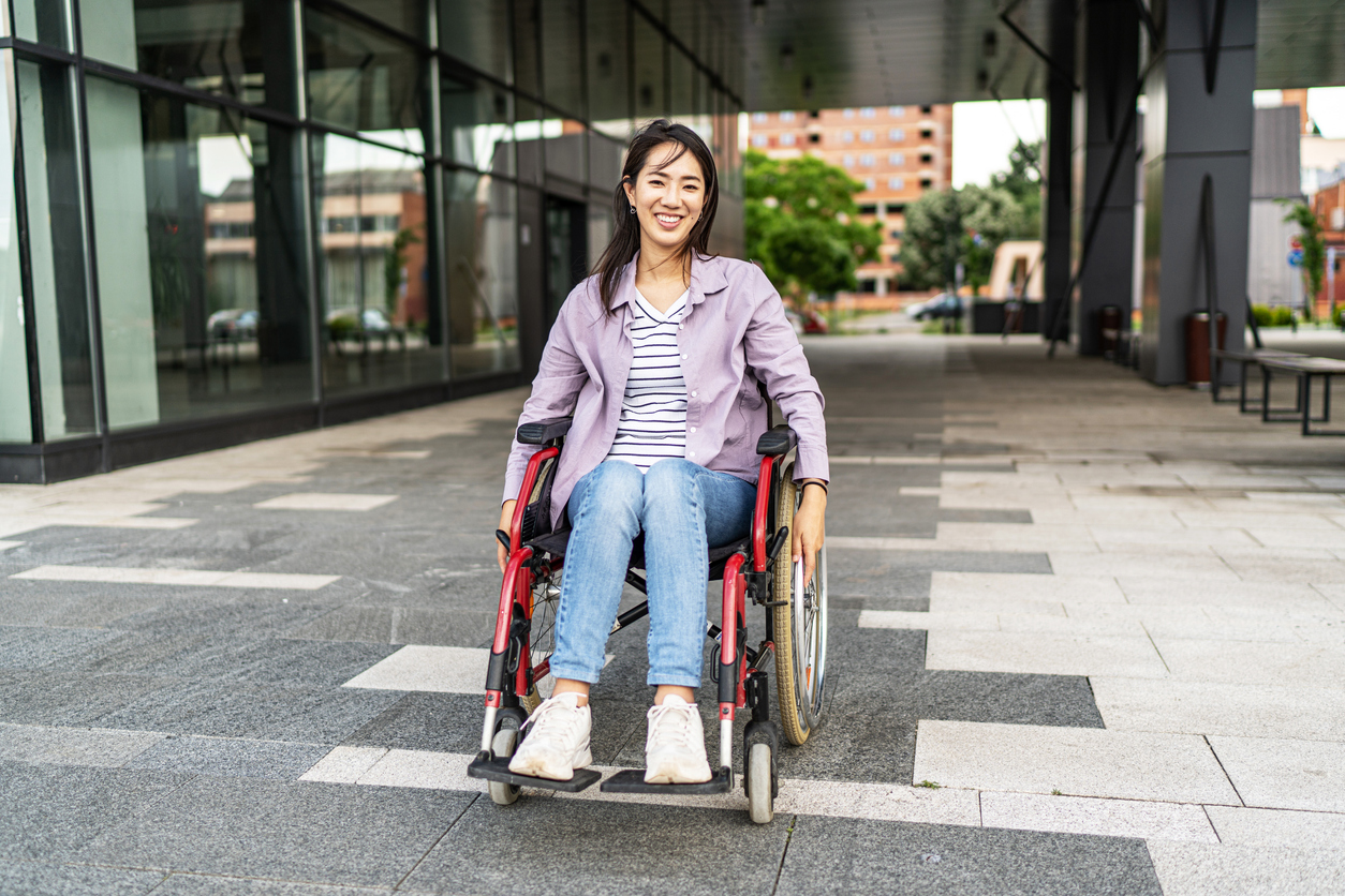 Young beautiful Asian woman in wheelchair outdoors